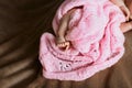 Cute little legs of a newborn girl with tiny fingers in a soft pink scarf