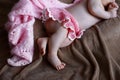 Cute little legs of a newborn girl with tiny fingers in a soft pink skirt