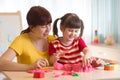 A cute little little girl and her mom playing with kinetic sand at home