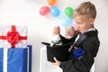 Cute little magician pulling rabbit out of hat indoors