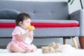 Cute little 7 months old multiracial, asian and caucasian, newborn baby girl sitting on floor in living room at home, having teeth Royalty Free Stock Photo