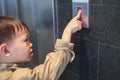 Asian 3 - 4 years old toddler boy kid standing in front of elevator trying to pressing lift / elevator button Royalty Free Stock Photo