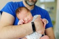 Cute little newborn baby boy in his fathers arms. Portrait of tiny new baby at home. Adorable son being held by his daddy Royalty Free Stock Photo