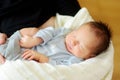 Cute little newborn baby boy sleeping in his mothers arms. Portrait of tiny new baby at home. Adorable son being held by his mommy Royalty Free Stock Photo