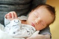 Cute little newborn baby boy sleeping in his mothers arms. Portrait of tiny new baby at home. Adorable son being held by his mommy Royalty Free Stock Photo