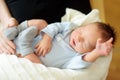 Cute little newborn baby boy sleeping in his mothers arms. Portrait of tiny new baby at home. Adorable son being held by his mommy Royalty Free Stock Photo