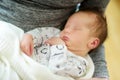 Cute little newborn baby boy sleeping in his mothers arms. Portrait of tiny new baby at home. Adorable son being held by his mommy Royalty Free Stock Photo