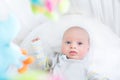 Cute little newborn baby in crib with colorful toys