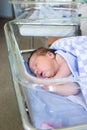 Cute little newborn baby sleeping in hospital bed, folded hands with open mouth, lying under blanket Royalty Free Stock Photo