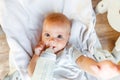 Cute little newborn girl drinking milk from bottle and looking at camera on white background. Infant baby sucking eating Royalty Free Stock Photo