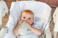 Cute little newborn girl drinking milk from bottle and looking at camera on white background. Infant baby sucking eating Royalty Free Stock Photo