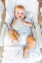 Cute little newborn girl drinking milk from bottle and looking at camera on white background. Infant baby sucking eating Royalty Free Stock Photo