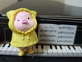 Cute little pig in yellow raincoat on piano model made of paper