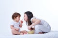 Cute little playful sisters eating yummy pasta in white studio background