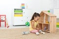 Cute little playing with toys near wooden house on floor at home, space for text Royalty Free Stock Photo