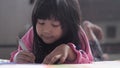 Cute little pre schooled Asian girl learning by plays and drawing with color marker on book