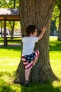 Cute little pre-schooler sizing up a tree in the park for climbing Royalty Free Stock Photo