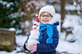 Cute little preschool girl with glasses making mini snowman. Adorable healthy happy child playing and having fun with