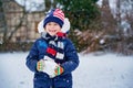 Cute little preschool girl outdoors in winter park . Adorable healthy happy child playing and having fun with snow, outdoors on Royalty Free Stock Photo