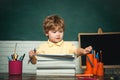 Cute little preschool kid boy study in a classroom. Funny little kid pointing up on blackboard - school concept. Kid is Royalty Free Stock Photo