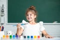 Cute little preschooler child girl drawing at school. Child girl painting on elementary school. Funny kids emotions.