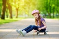 Cute little preteen girl wearing helmet sitting on a skateboard