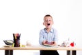 Cute little school boy with huge smile sitting at his desk on white background. Happy intelligent children in shirt with blue eye Royalty Free Stock Photo