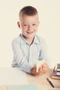 Cute little school boy with huge smile sitting at his desk on white background. Happy intelligent children in shirt with blue eyes Royalty Free Stock Photo