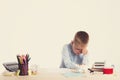 Cute little school boy with sad face sitting at his desk on white background.Unhappy intelligent children in shirt with blue eyes Royalty Free Stock Photo