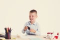 Cute little school boy with sad face sitting at his desk on white background.Unhappy intelligent children in shirt with blue eyes Royalty Free Stock Photo