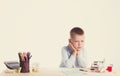 Cute little school boy with sad face sitting at his desk on white background.Unhappy intelligent children in shirt with blue eyes Royalty Free Stock Photo