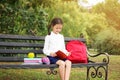 Cute little school child with stationery on bench in park Royalty Free Stock Photo