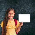 Little school girl holding mock up white blank paper against blackboard