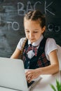 Cute school girl sitting at the desk and using computer. Back to school and online lessons concept Royalty Free Stock Photo