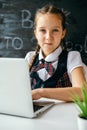 Cute school girl sitting at the desk and using computer. Back to school and online lessons concept Royalty Free Stock Photo