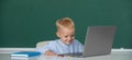 Cute little school kid boy study in a classroom. Funny blonde pupil on blackboard. Royalty Free Stock Photo