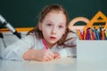 Cute little schoolgirl drawing an house and looking at camera Royalty Free Stock Photo