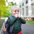 Cute little schoolboy with magnifying glass studying outdoors on sunny day Royalty Free Stock Photo