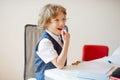 Cute little schoolboy sitting at a school desk with dreaming views.