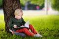 Cute little schoolboy sitting under tree and studying . Back to school concept. Royalty Free Stock Photo