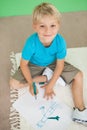 Cute little schoolboy smiling at camera while drawing