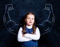 Cute little schoolgirl against chalkboard with strong arms Royalty Free Stock Photo