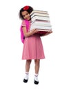 Cute little schoolgirl carrying stack of books Royalty Free Stock Photo