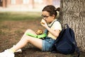 Cute little schoolgirl eating from lunch box outdoor under the tree. Food for kids Royalty Free Stock Photo