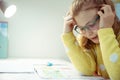 Cute little schoolgirl in glasses making her homework at home during pandemic homeschooling Royalty Free Stock Photo