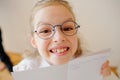 Cute little schoolgirl in glasses shows her copybook. Royalty Free Stock Photo