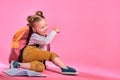 Cute little schoolgirl pointing at something on pink background Royalty Free Stock Photo