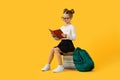 Cute Little Schoolgirl Sitting On Book Stack And Reading Task in Workbook Royalty Free Stock Photo