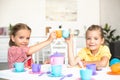 cute little sisters clinking toy cups while pretending to have tea party together