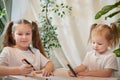 Cute little sisters are painting on table. Preschooler, 4 and 8 years child in living room. Small girl kids doing